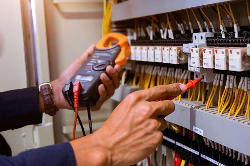 Electrician measurements with multimeter testing current electric in control panel